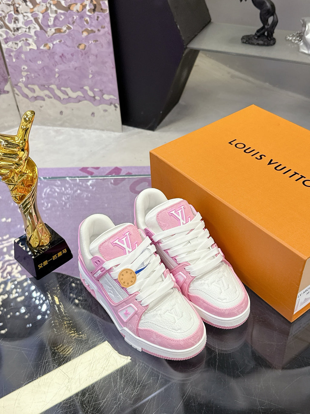 Pink and white Louis Vuitton sneakers on orange box, pair close-up