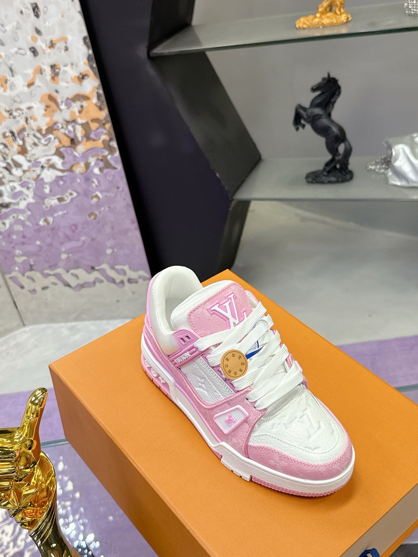 Pink and white Louis Vuitton sneaker on orange box, lace-up with logo
