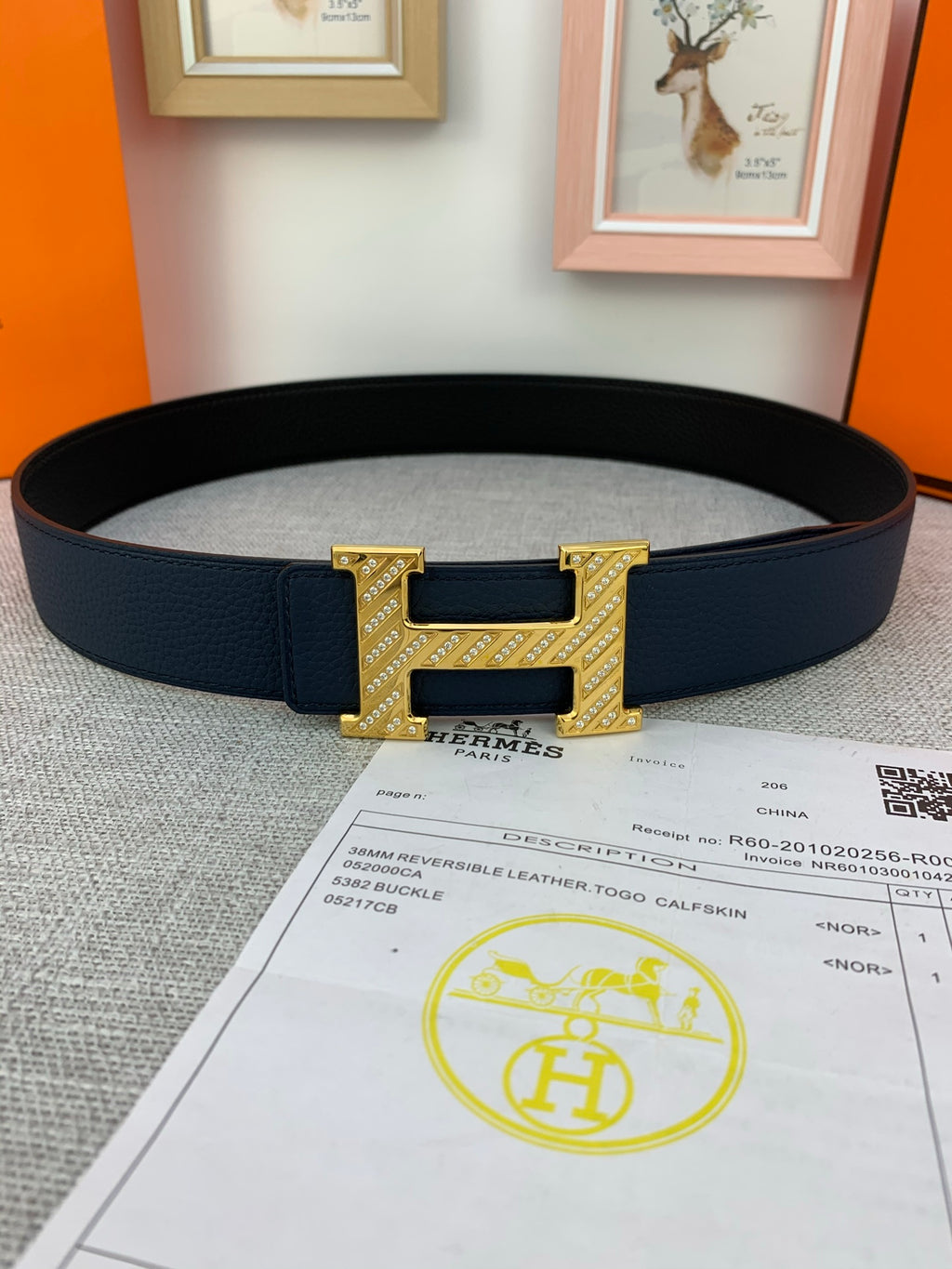 Hermes belt in dark blue with gold-tone H buckle and keeper, laid on receipt
