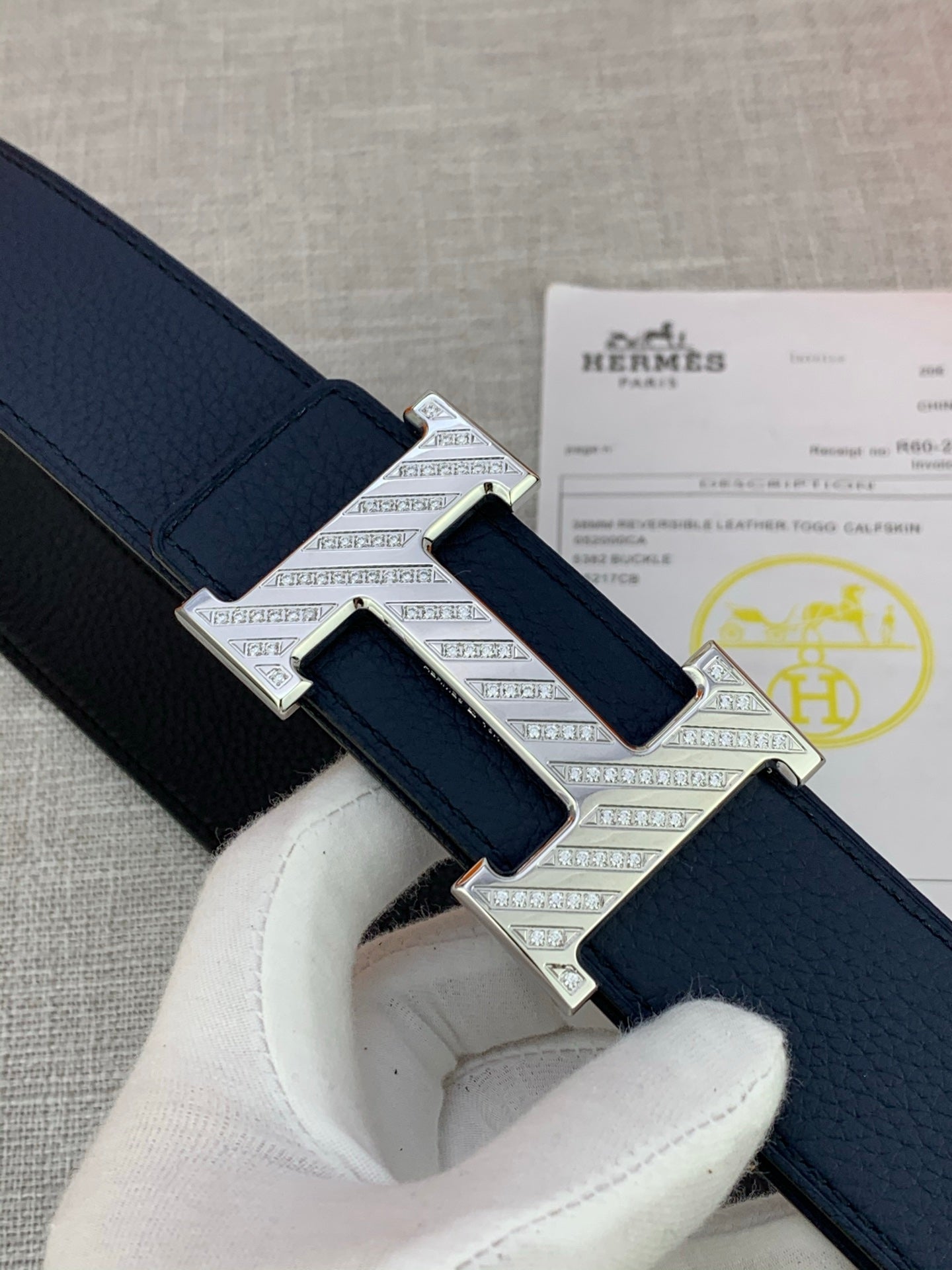 Hermes belt buckle detail in silver-tone on dark blue leather strap with keeper