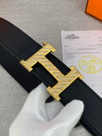 Hermes belt, black textured strap with gold-tone H buckle close-up