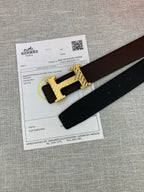 Hermes belt with gold H buckle and dark leather strap beside product paperwork