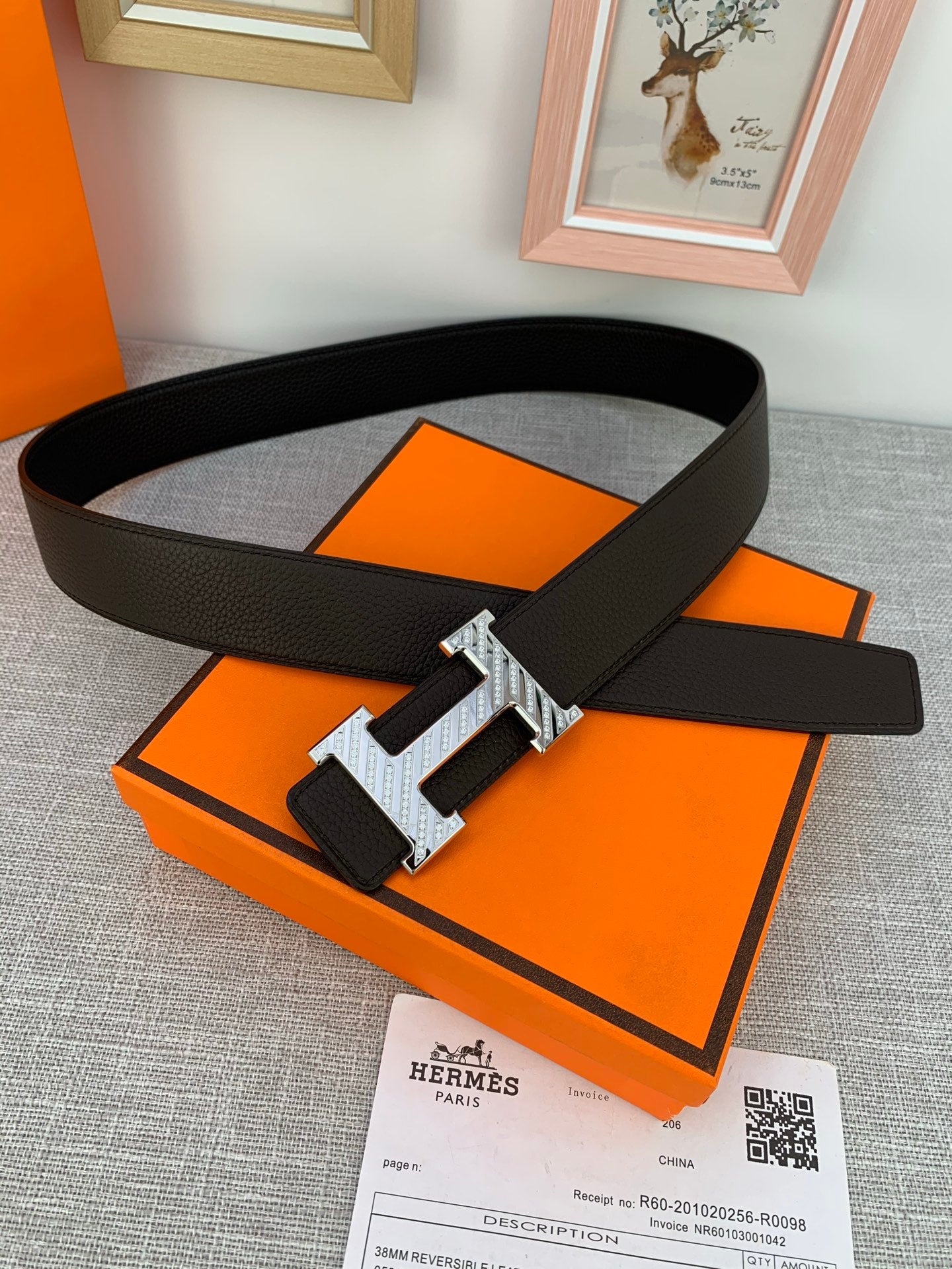 Hermes belt with dark leather strap and silver double H buckle, laid on box