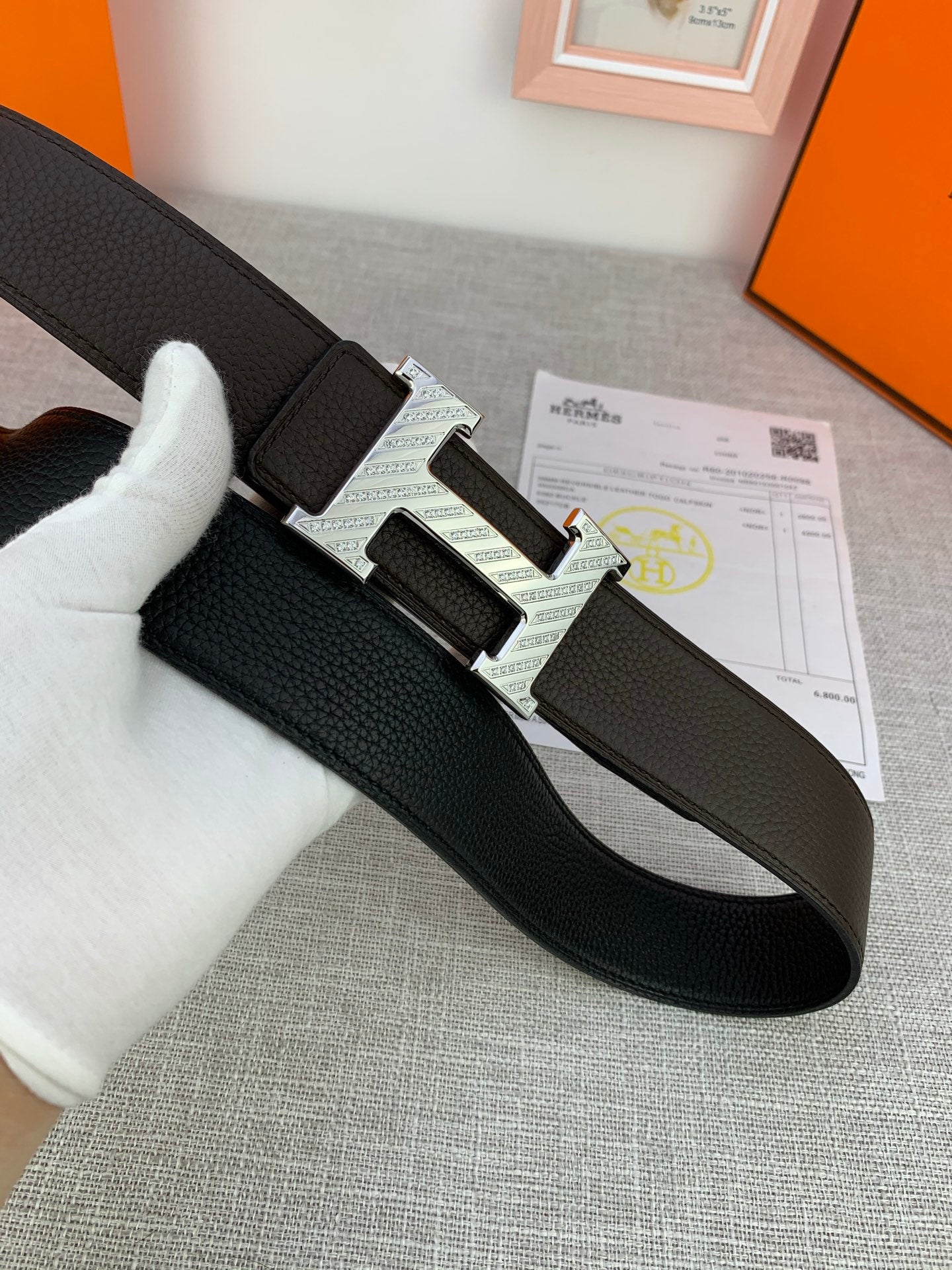 Hermes leather belt with dark strap and silver H buckle, shown flat