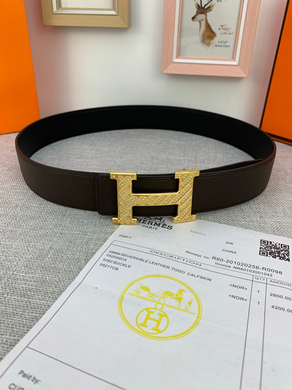 Hermes belt with dark leather strap and gold H buckle, shown with receipt