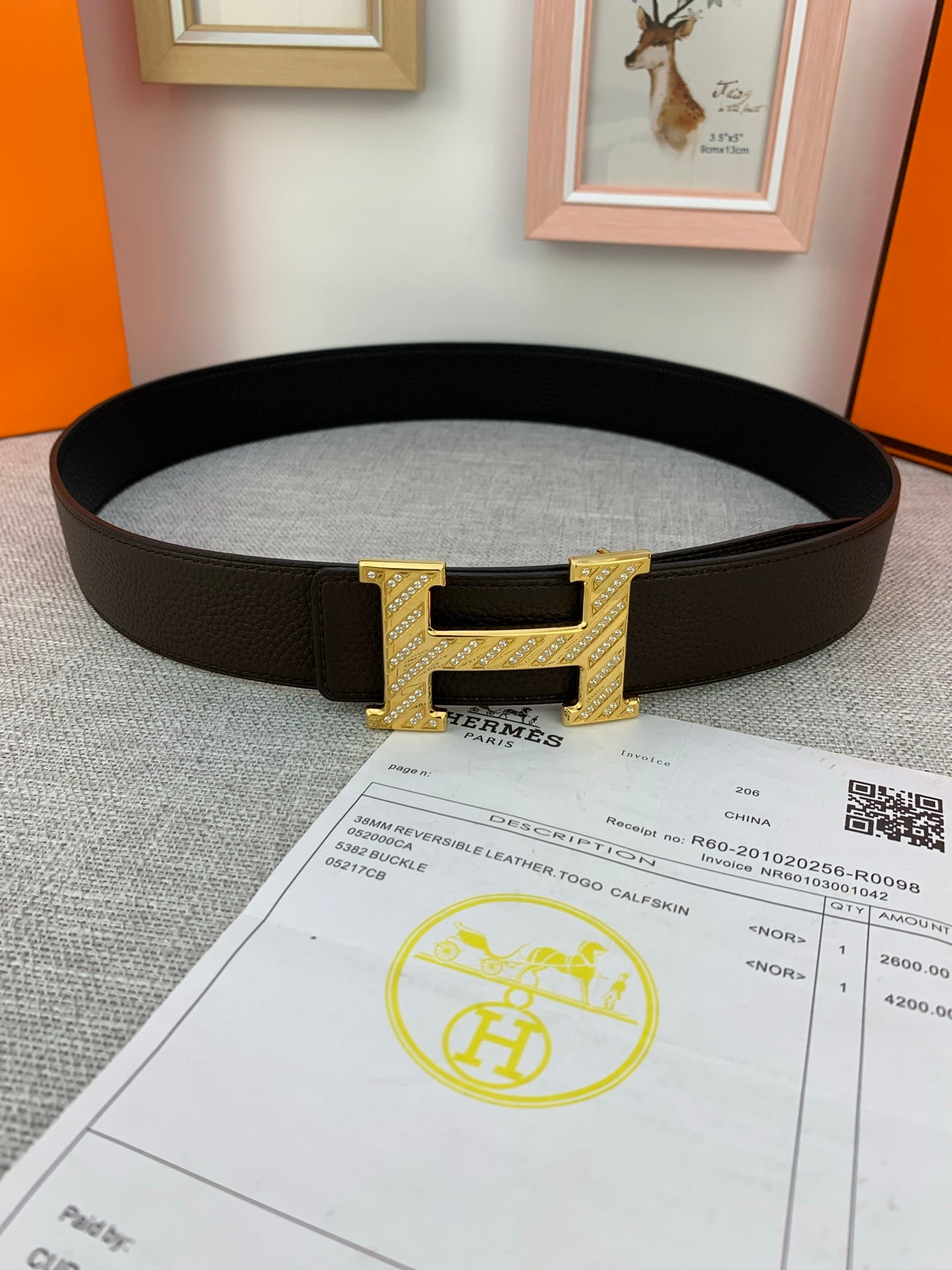 Hermes belt with dark leather strap and gold H buckle, shown with receipt