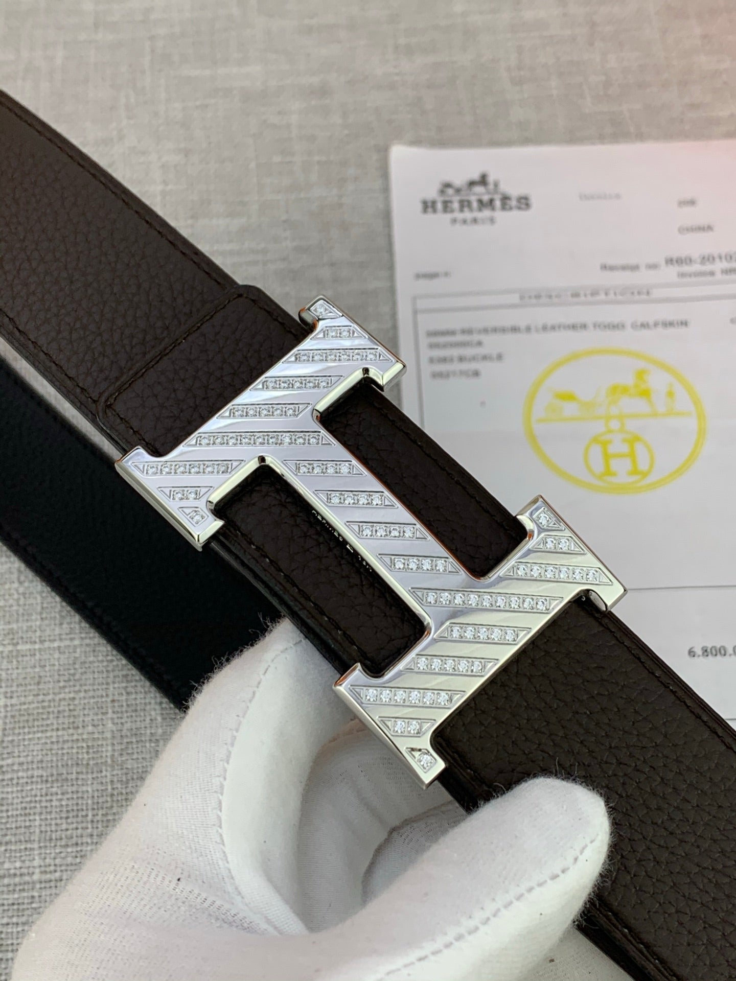 Hermes belt close-up: dark leather strap with silver buckle and perforated texture