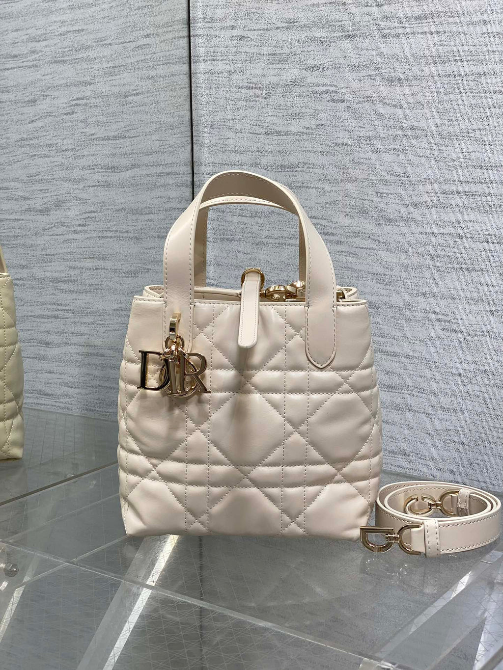 Dior cream quilted mini handbag with top handle and gold logo hardware, plus crossbody strap