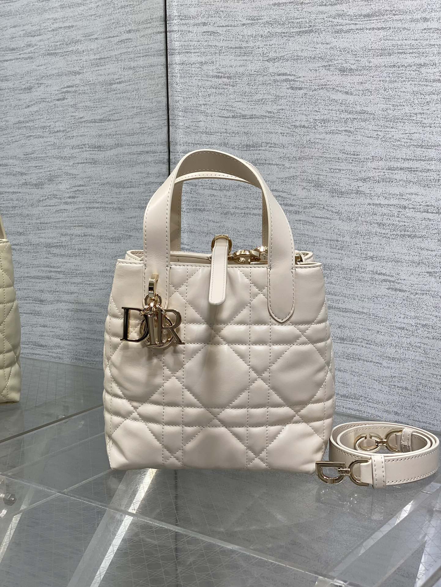 Dior cream quilted mini handbag with top handle and gold logo hardware, plus crossbody strap