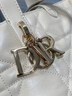 Dior cream leather strap with gold-tone clasp and “D I O R” logo charm on quilted bag