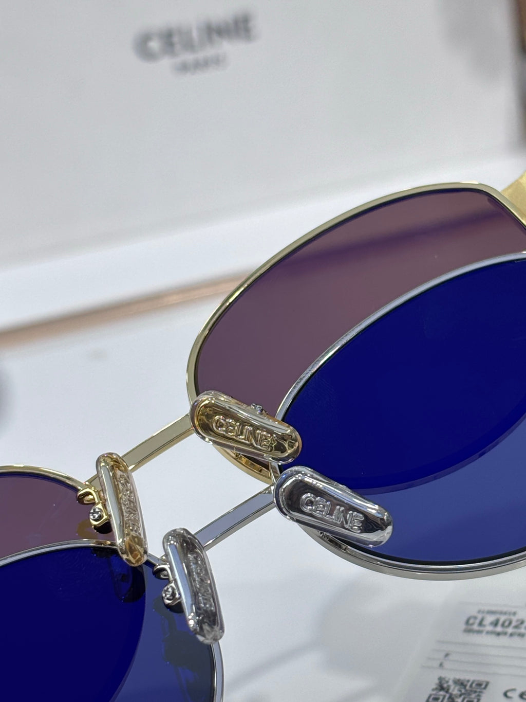 Sunglasses close-up, gold hinges, dark blue lenses, curved metal frame