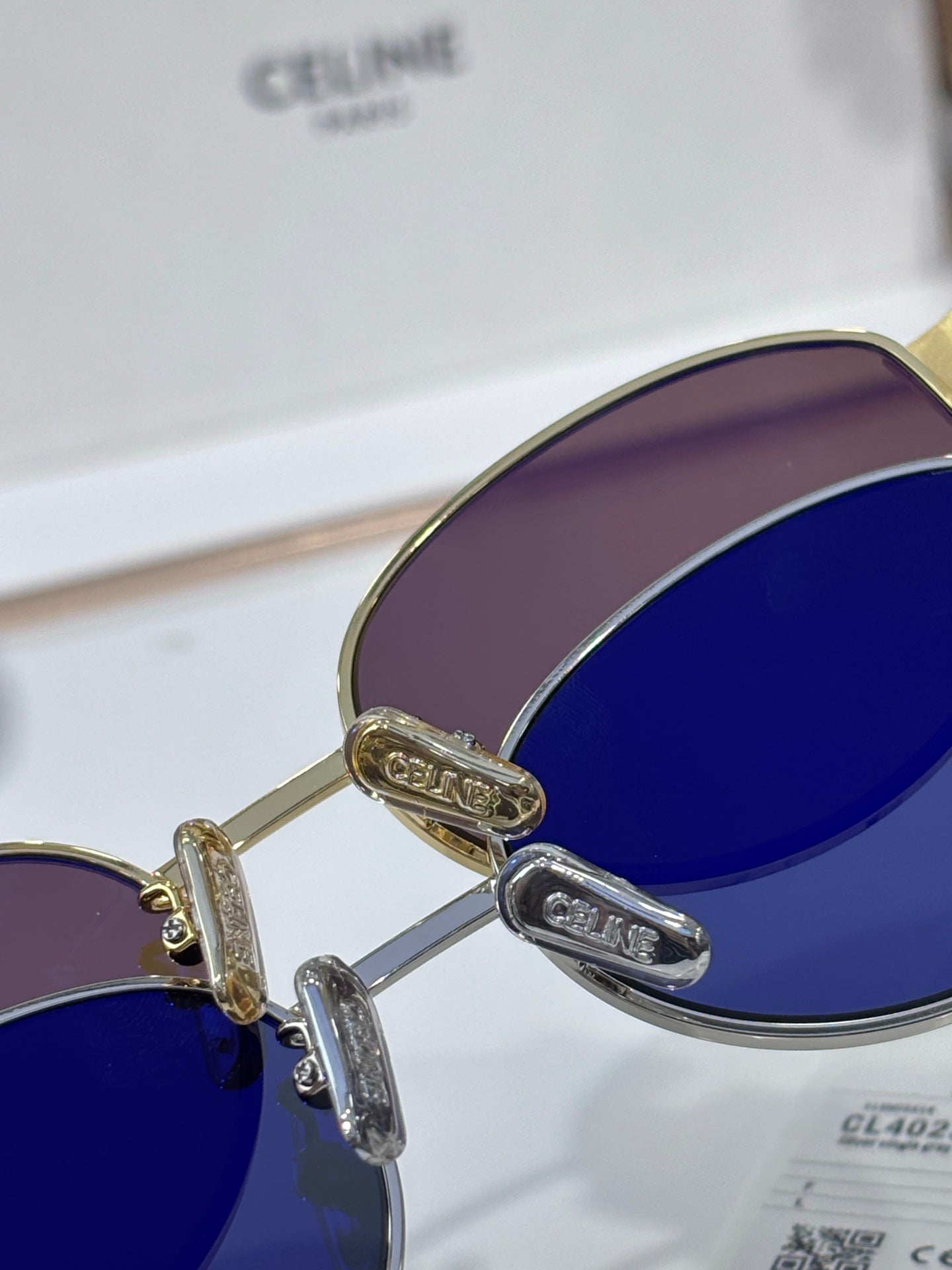 Sunglasses close-up, gold hinges, dark blue lenses, curved metal frame