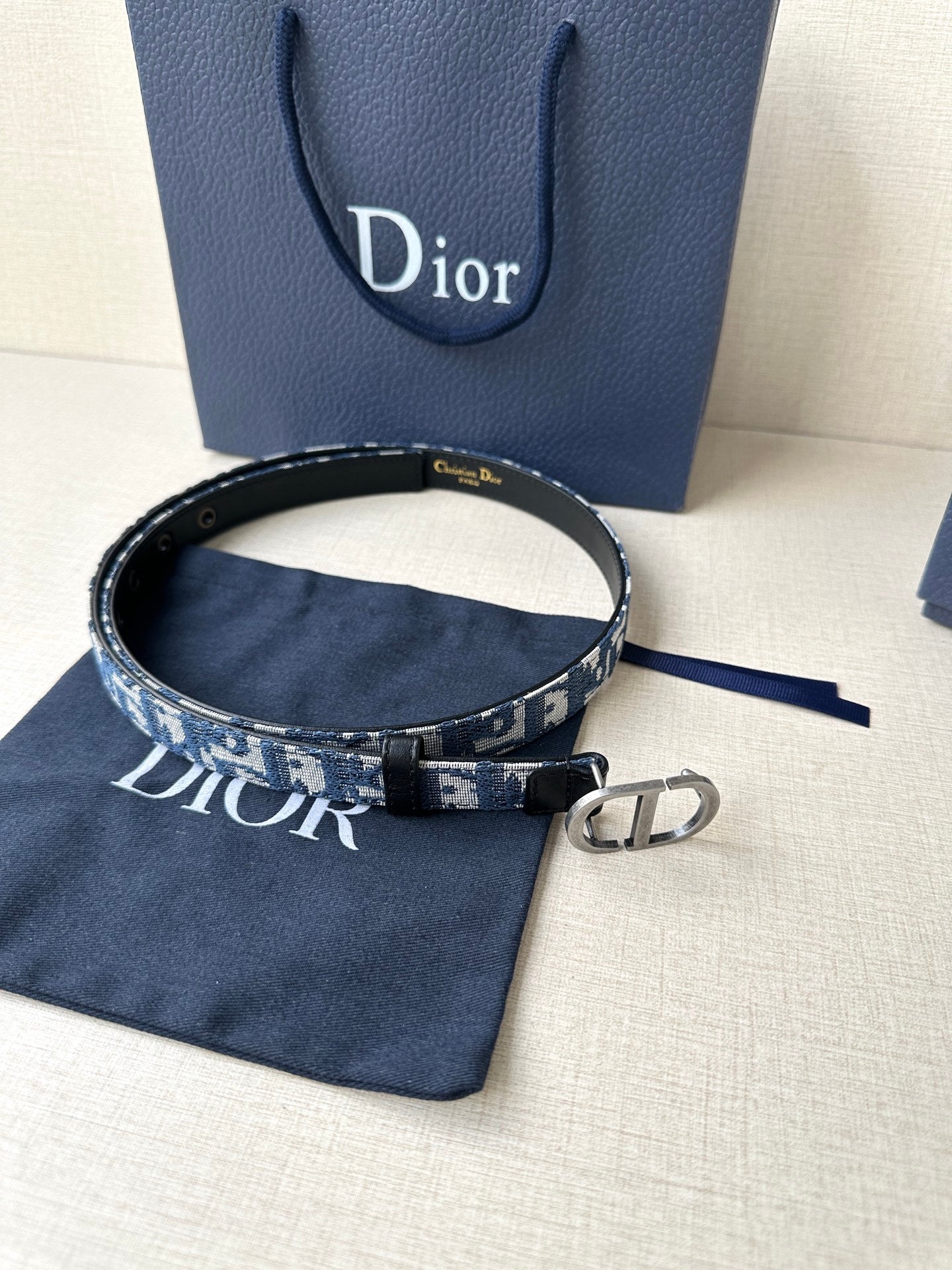 Dior belt with blue monogram strap and silver CD buckle on black leather.