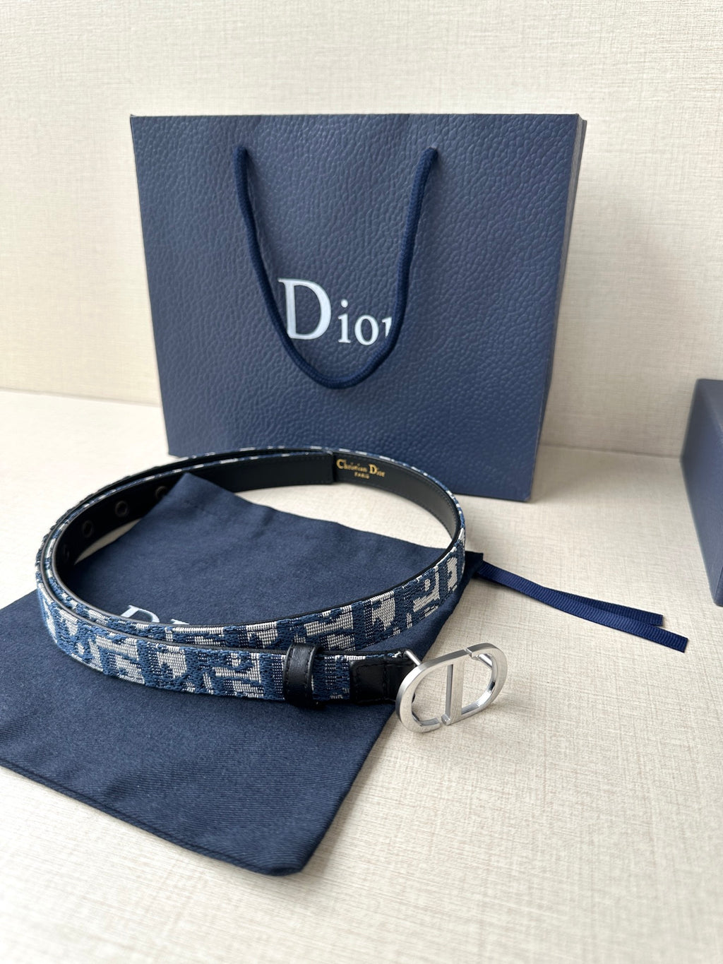 Dior belt on dark fabric pouch, blue patterned strap with silver double-ring buckle