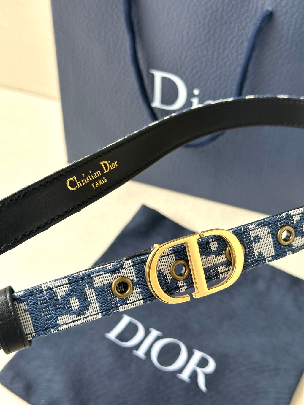 Dior belt close-up: blue monogram strap, gold CD buckle and metal eyelets