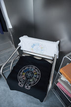 Folded white and black T-shirts with matching circular rhinestone logos