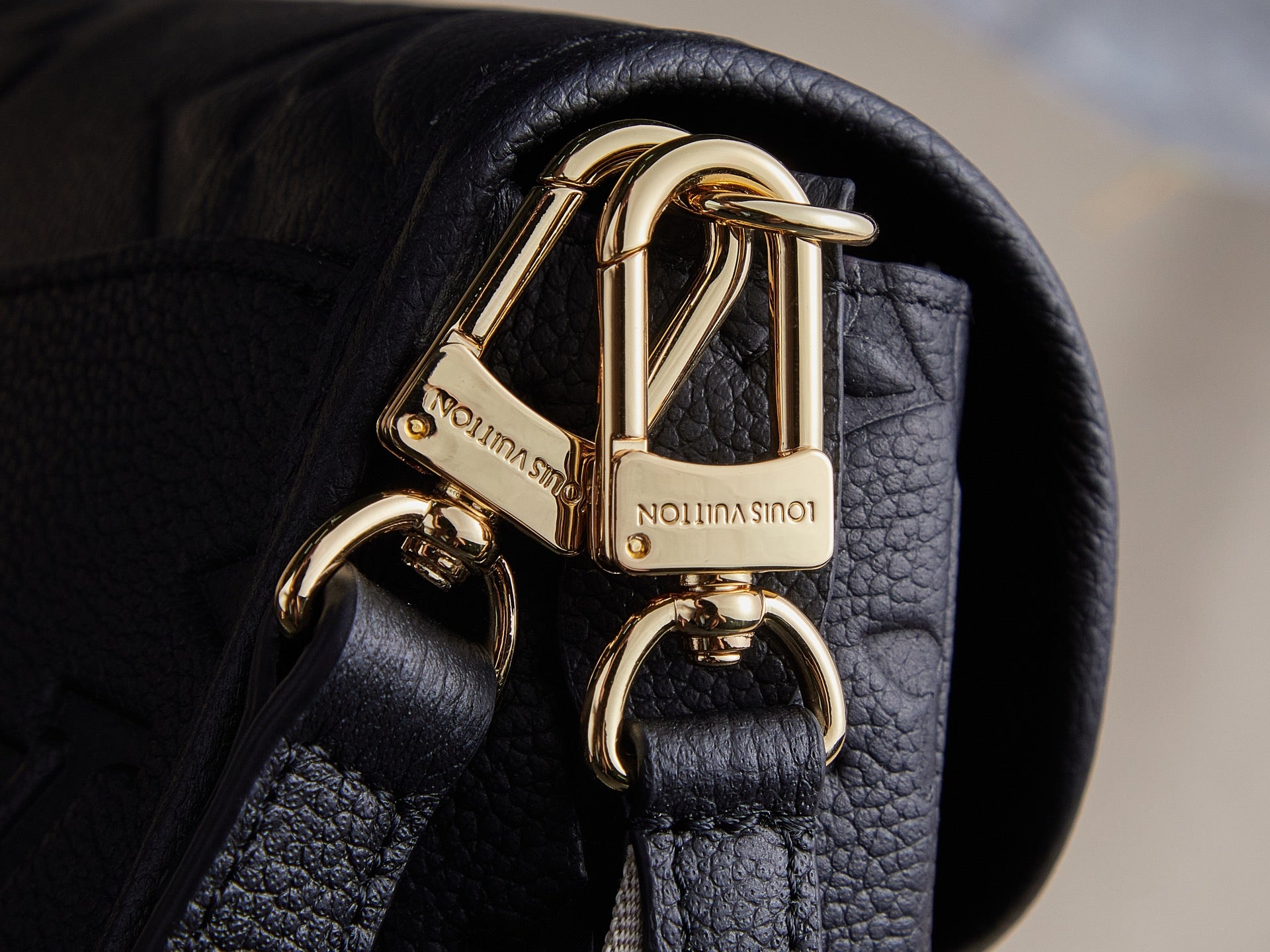 Louis Vuitton bag hardware, gold clasp on textured dark leather