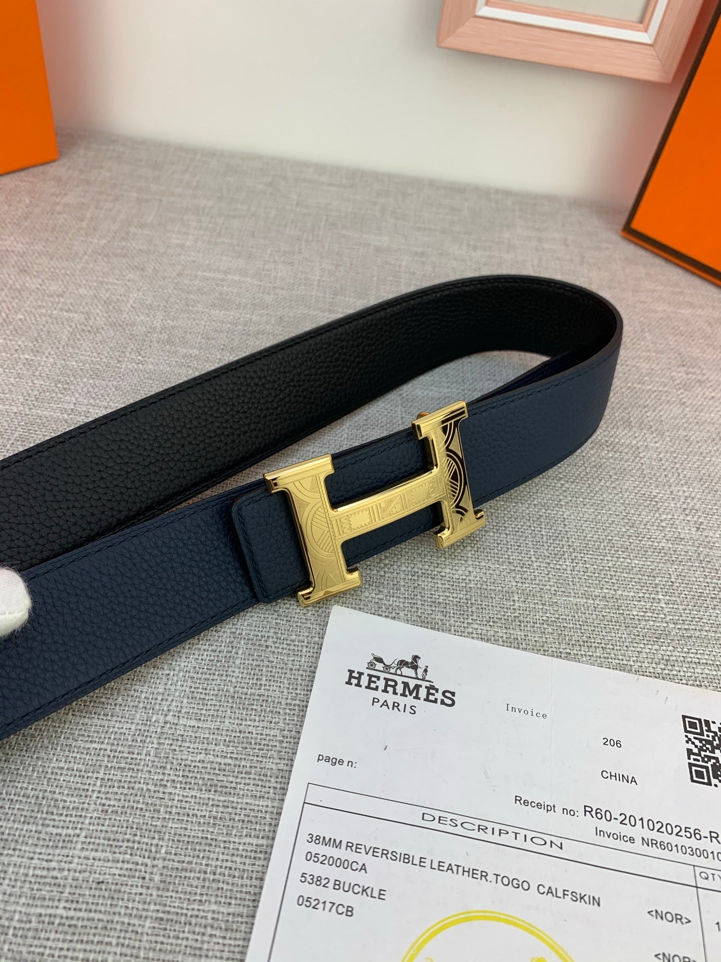 Hermes belt close-up: dark navy strap with gold-tone H buckle and keeper