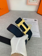 Hermes belt with dark navy strap and silver-tone H buckle, hands holding it