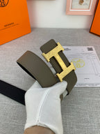 Leather belt with gold-tone buckle, olive strap front with dark reverse side visible.