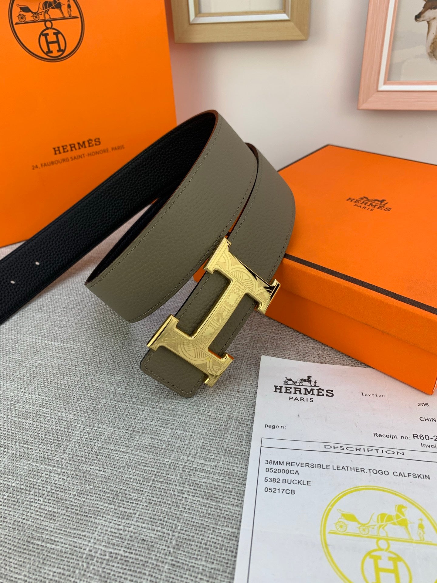 Leather belt with gold-tone buckle lying on paperwork, olive strap and dark side.