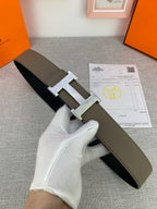 Leather Hermes belt with metallic buckle, olive strap over dark strap side.