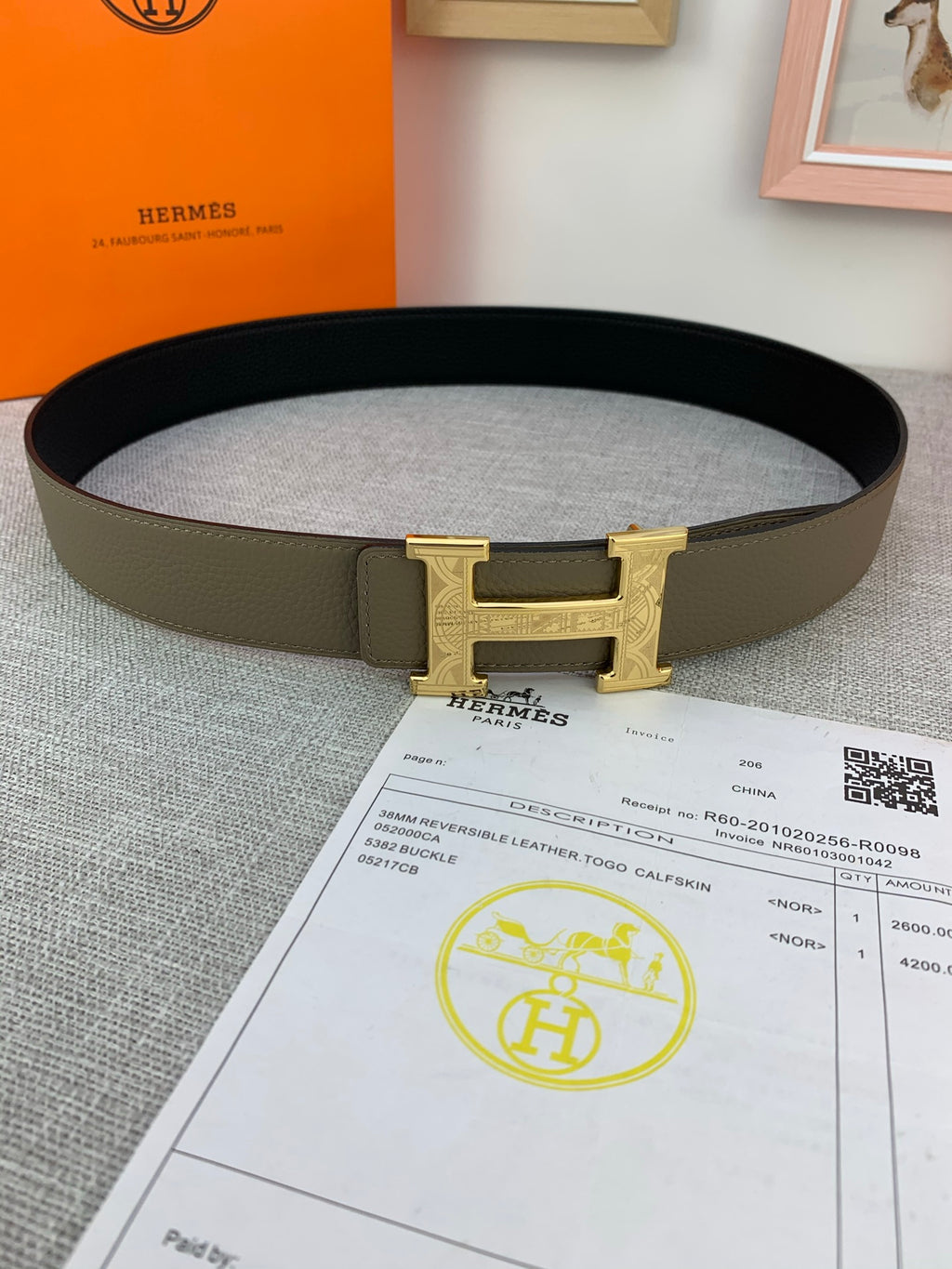 Leather belt with gold-tone buckle and olive band, folded on paperwork.