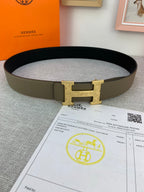 Leather belt with gold-tone buckle and olive band, folded on paperwork.