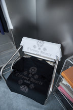 Folded T-shirts on rack: white and dark blue each with rhinestone-style crest