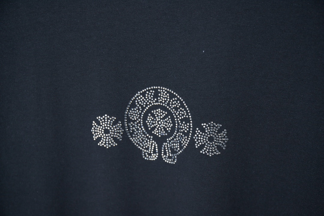 Dark blue T-shirt chest emblem with rhinestone-style circular logo and floral motifs