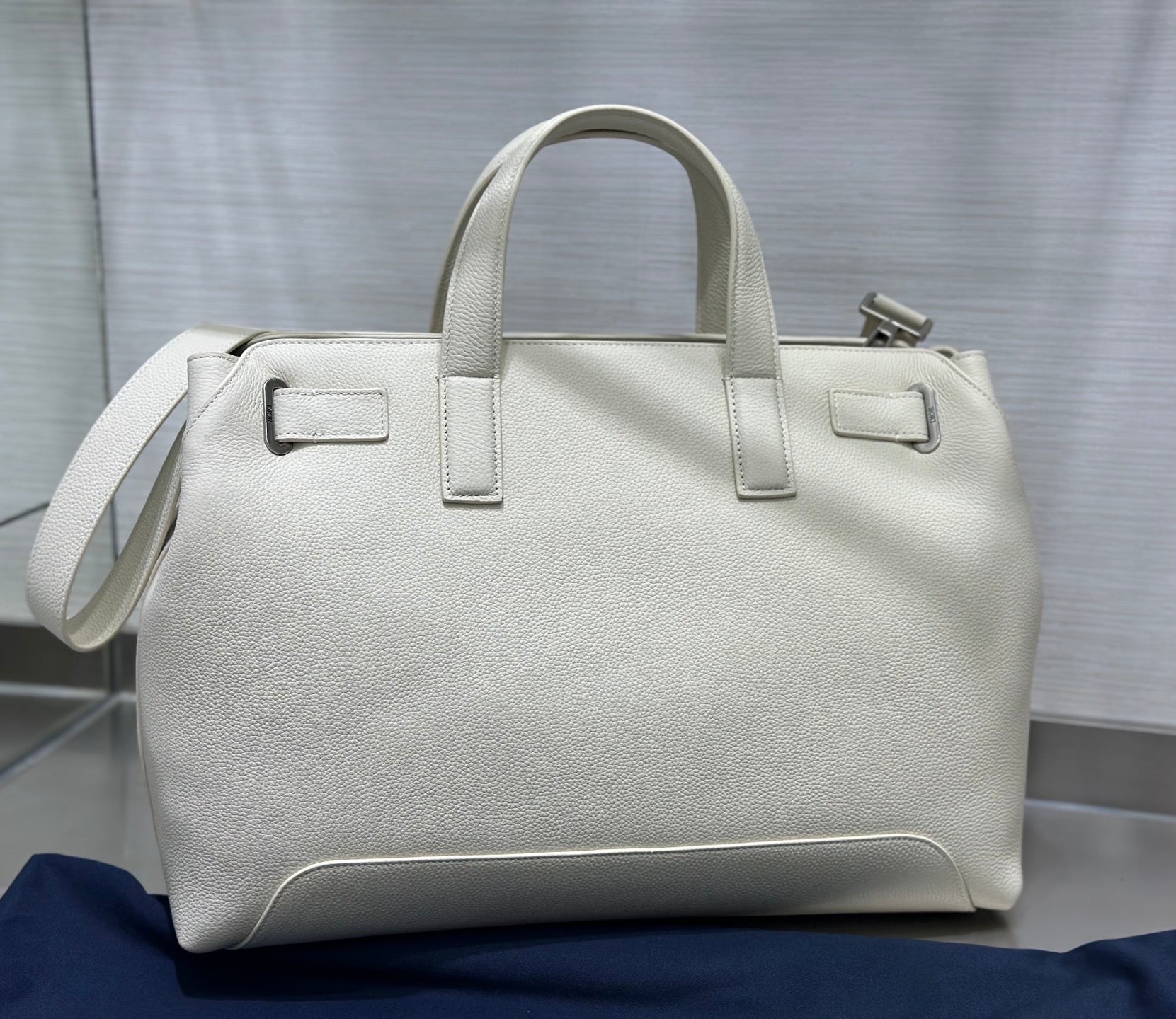 White Dior handbag with top handles and side strap, structured rectangular shape