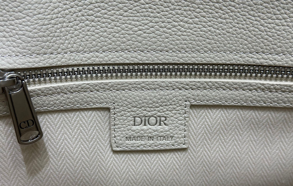 White Dior handbag zipper pocket with “CD” charm and DIOR Made in Italy label