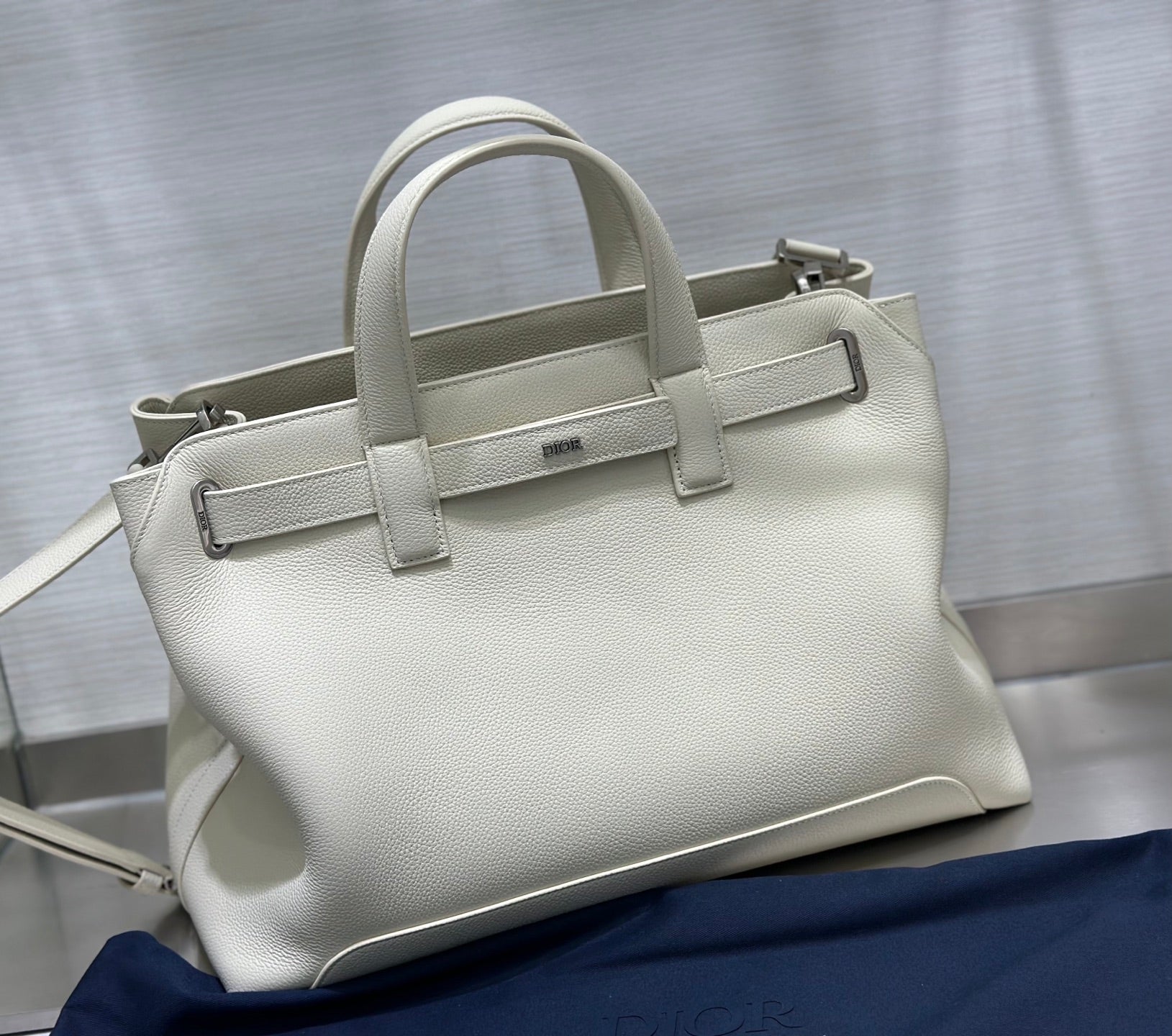 White Dior tote handbag with top handles, front strap, and silver-tone hardware