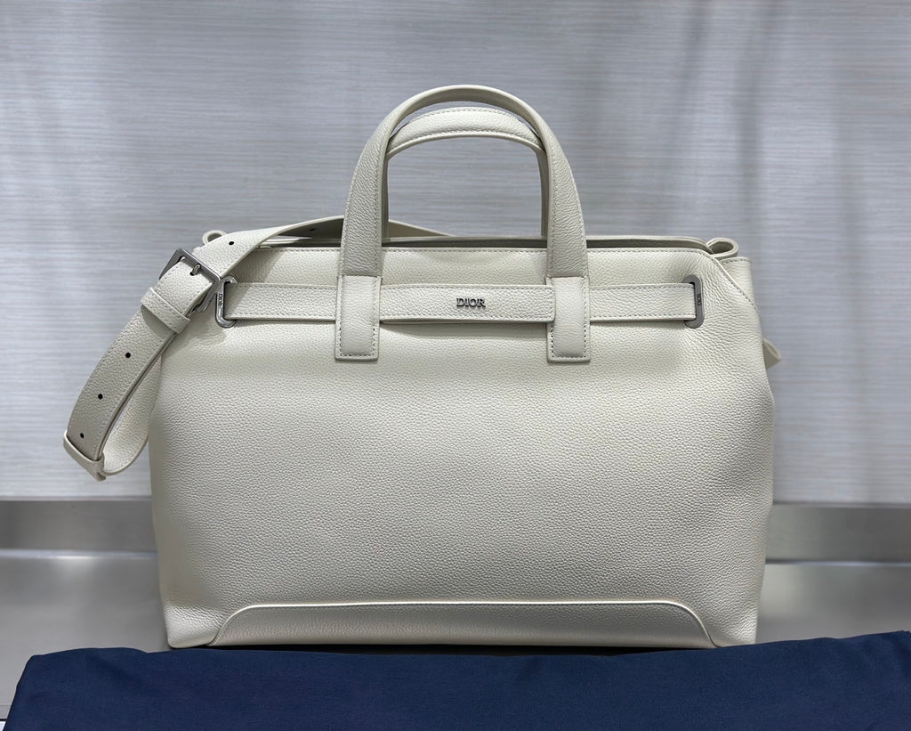 White Dior handbag front view with top handles, front strap, and side tie