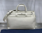 White Dior handbag front view with top handles, front strap, and side tie