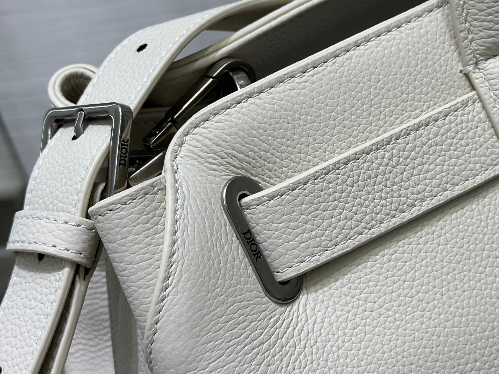 White Dior handbag close-up with front pocket tab and strap hardware