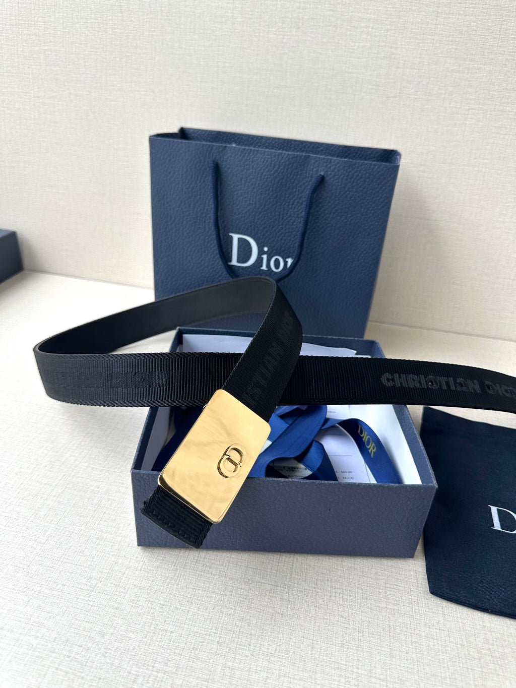 Dior belt with dark strap and gold rectangular buckle with Dior emblem