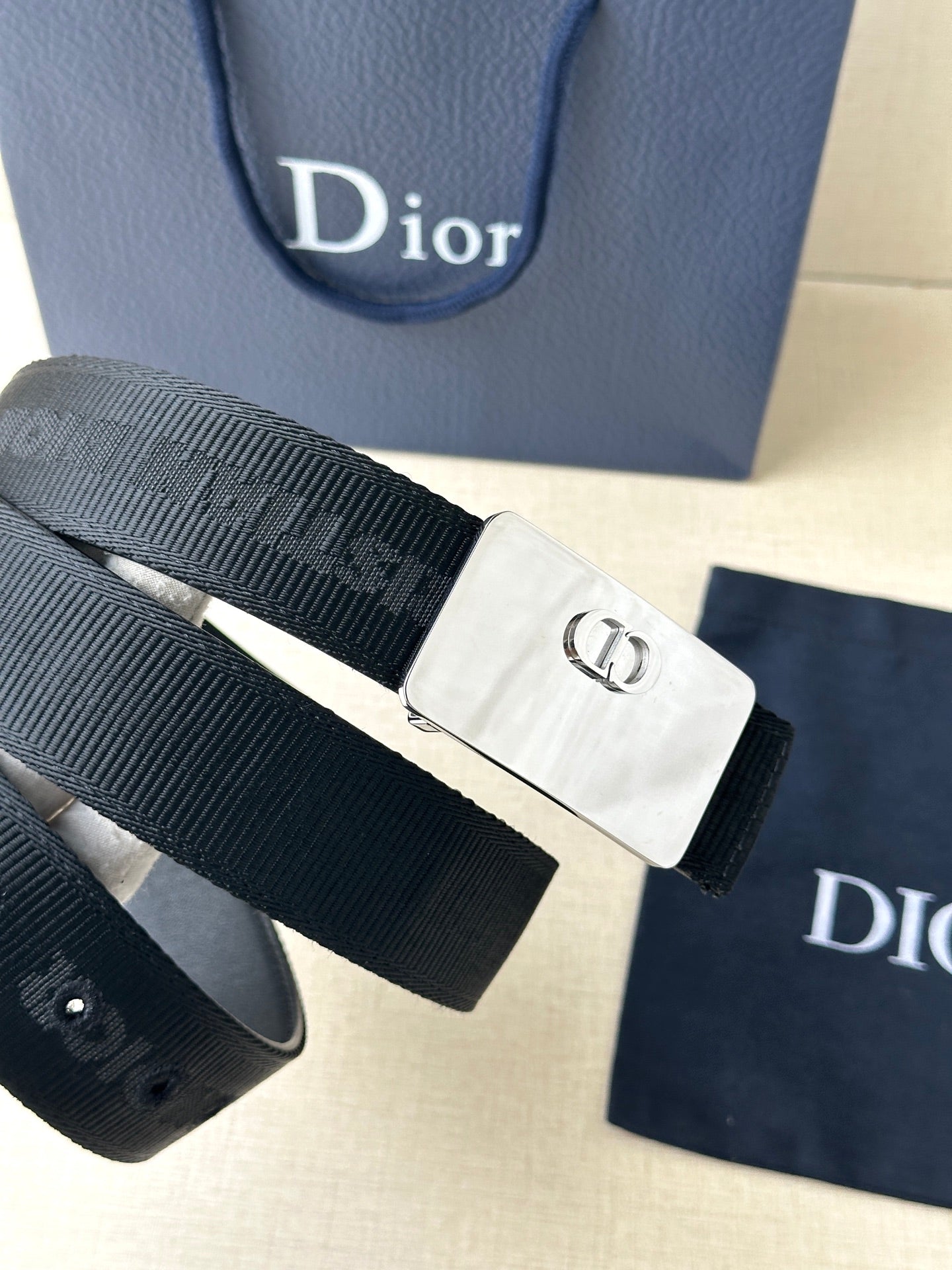 Dior belt close-up with dark ribbed strap and silver rectangular buckle