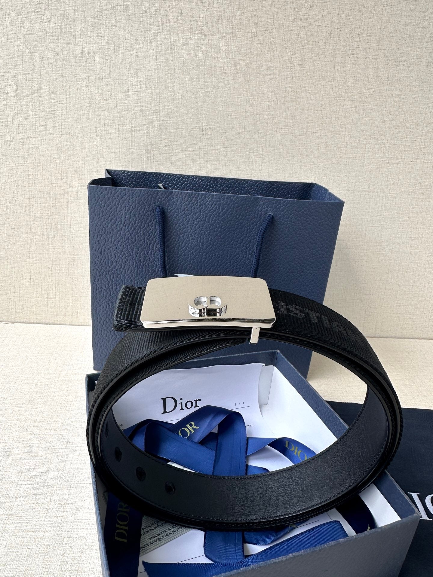 Dior belt with black textured strap and silver buckle plate with Dior emblem