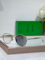 Bottega Veneta round sunglasses with dark lenses and gold-tone metal frame, metal temples