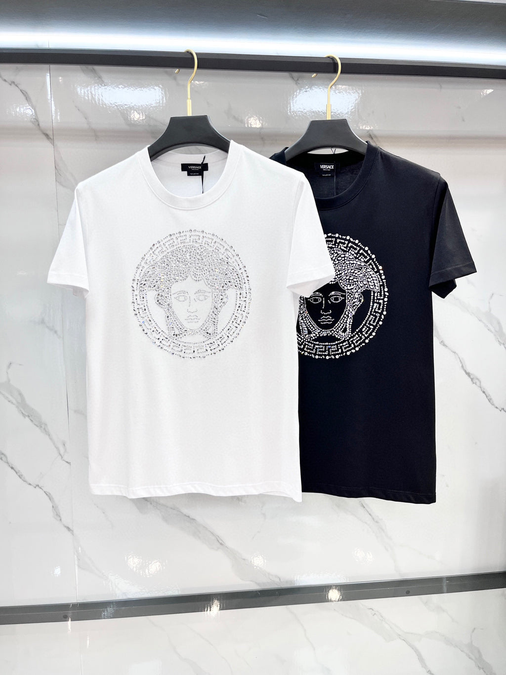 White and black Versace T-shirts with rhinestone Medusa-style front graphics