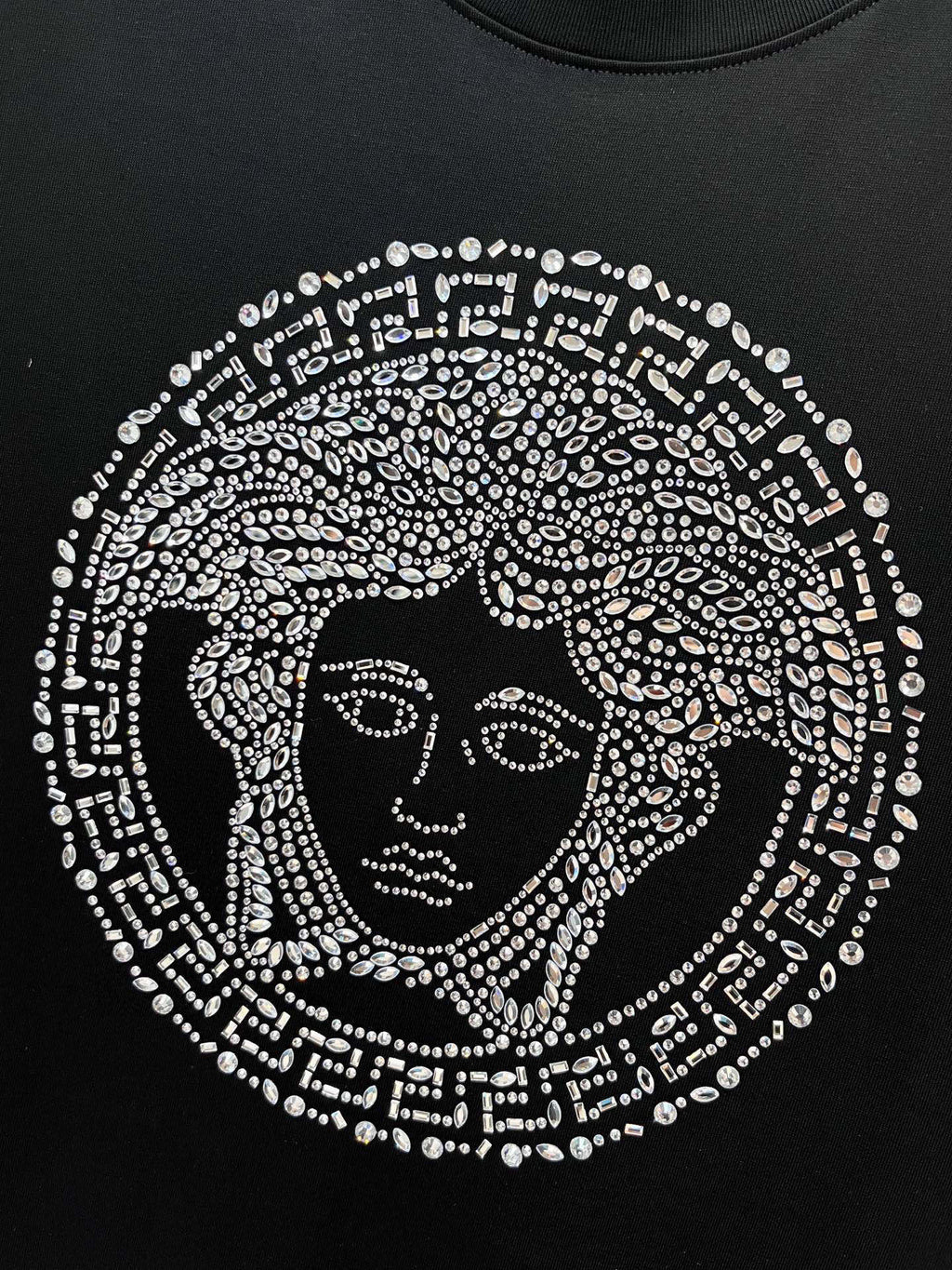 Black T-shirt with rhinestone Medusa face graphic centered on the chest