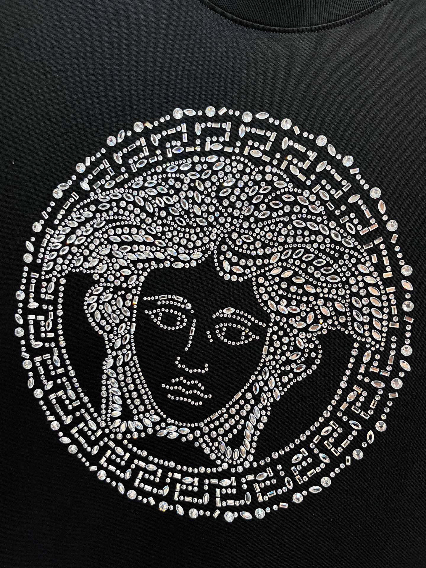 Black T-shirt with rhinestone Medusa face graphic centered on the chest