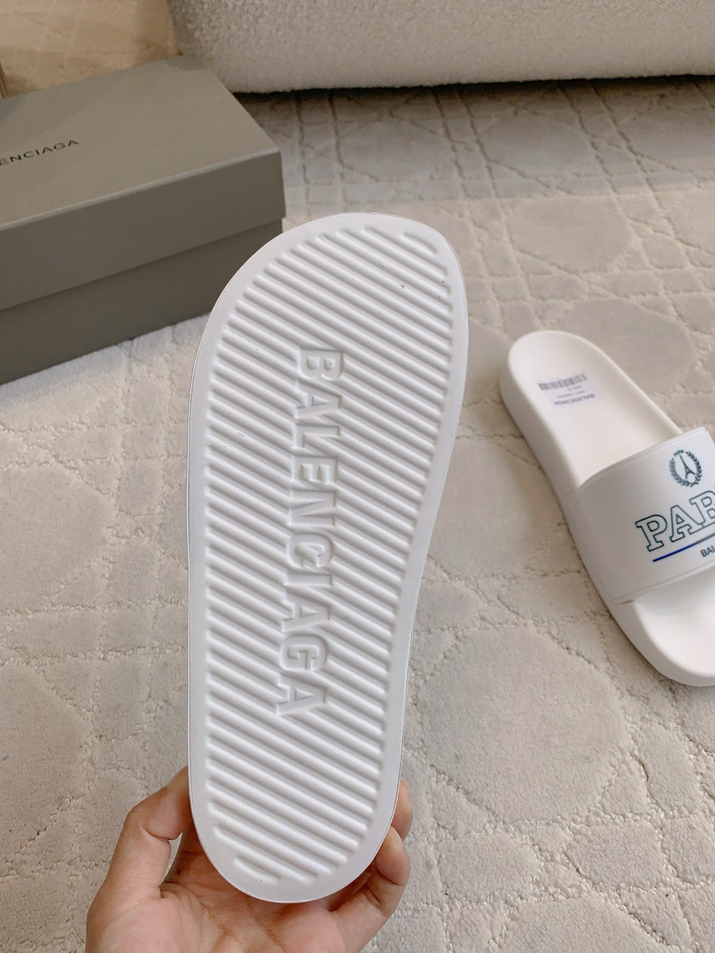 White slide sandal outsole with Balenciaga embossed on textured tread.