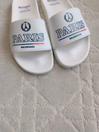 White slide sandals close-up: front straps with PARIS and Balenciaga branding.