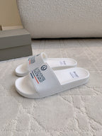 White slide sandals with side strap showing PARIS and Balenciaga branding.
