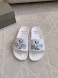 White slide sandals with wide strap, Balenciaga Paris logo on front.