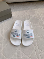 White slide sandals with wide strap, Balenciaga Paris logo on front.