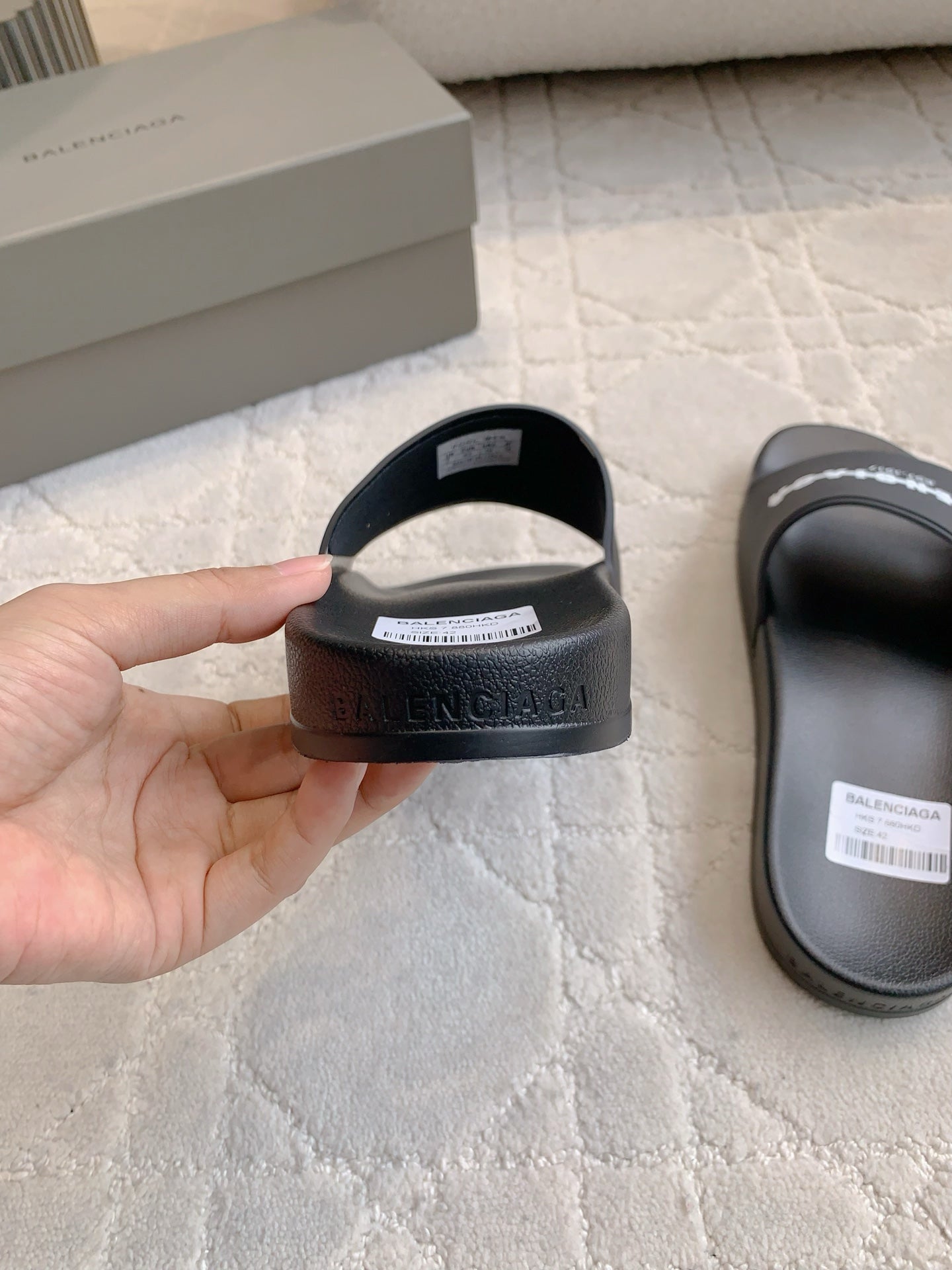 Black slide sandal heel with embossed logo text on the back strap