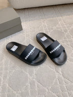 Pair of black slide sandals with wide strap and white logo print on top